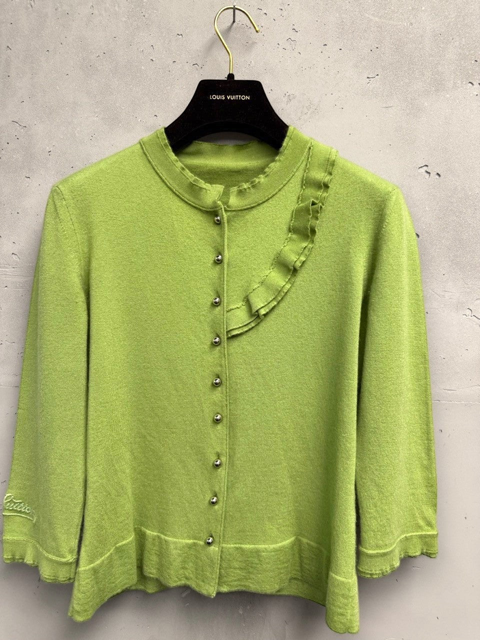 BERLIN VINTAGE CORNER lime green knit cardigan with ruffled neckline, silver buttons, and embroidered logo on sleeve.