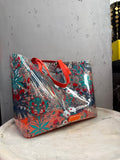 BERLIN VINTAGE CORNER Marc by Marc Jacobs transparent PVC tote bag with red and teal floral print and orange handles.