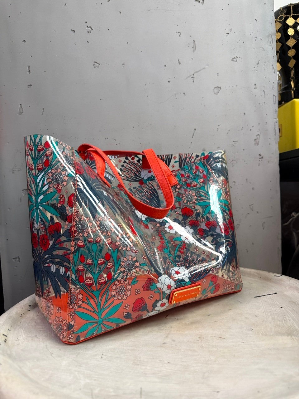 BERLIN VINTAGE CORNER Marc by Marc Jacobs transparent PVC tote bag with red and teal floral print and orange handles.