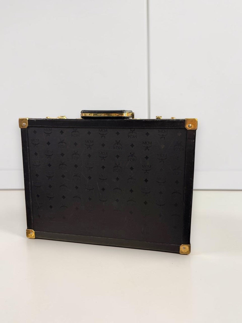BERLIN VINTAGE CORNER MCM vintage black leather hard shell briefcase with monogram pattern and gold-tone hardware.