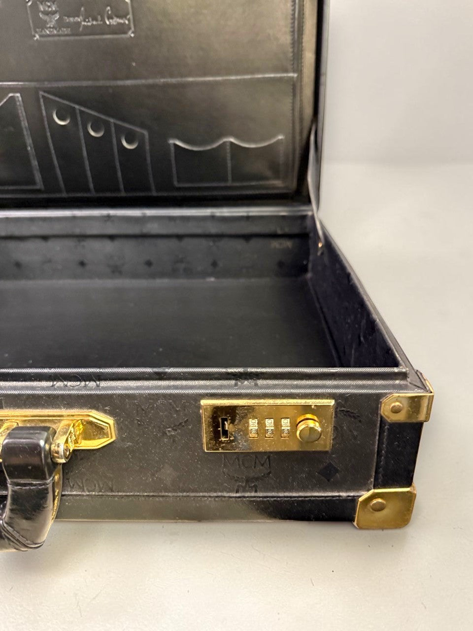 BERLIN VINTAGE CORNER MCM black leather hard shell briefcase with monogram pattern, gold hardware, and combination lock.