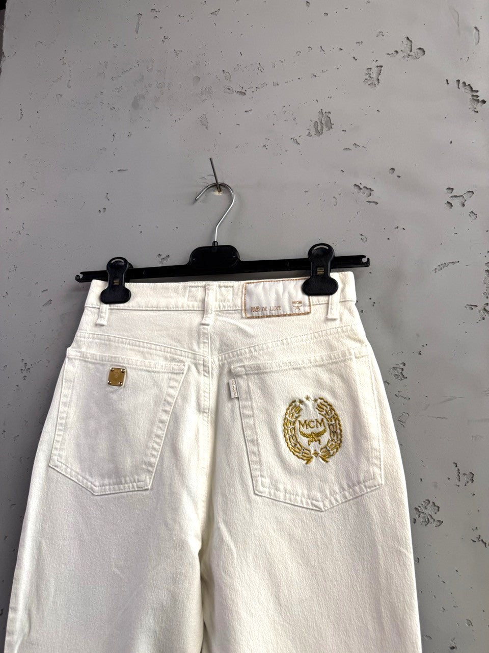 BERLIN VINTAGE CORNER off-white straight leg jeans with gold MCM logo embroidery and gold hardware.