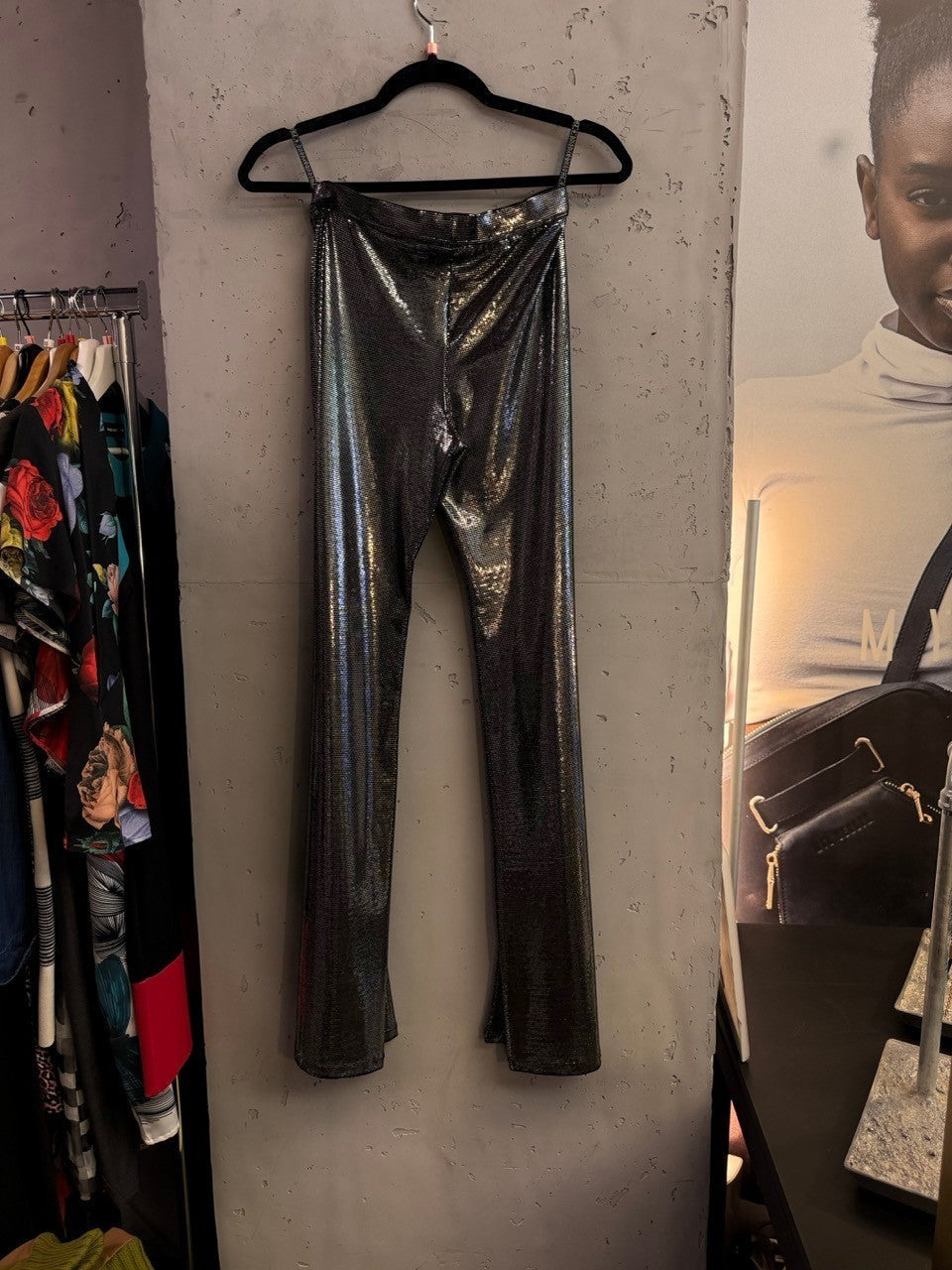 BERLIN VINTAGE CORNER metallic silver high-waisted trousers with a shimmering textured finish hanging on a rack.