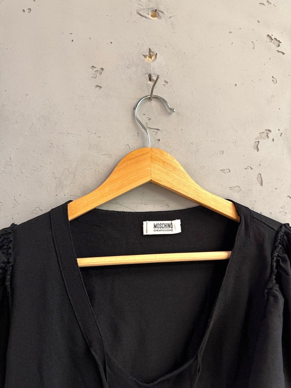 BERLIN VINTAGE CORNER black Moschino Cheap and Chic knit top with V-neck and flutter sleeves on a wooden hanger.