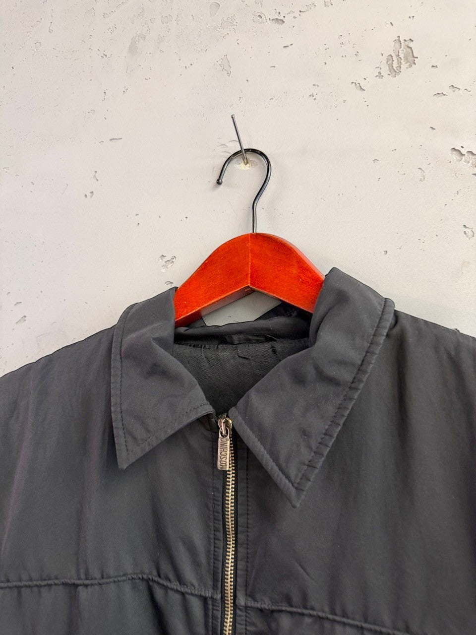 BERLIN VINTAGE CORNER black Moschino zip-up jacket with horizontal seam detailing and logo patch on sleeve.