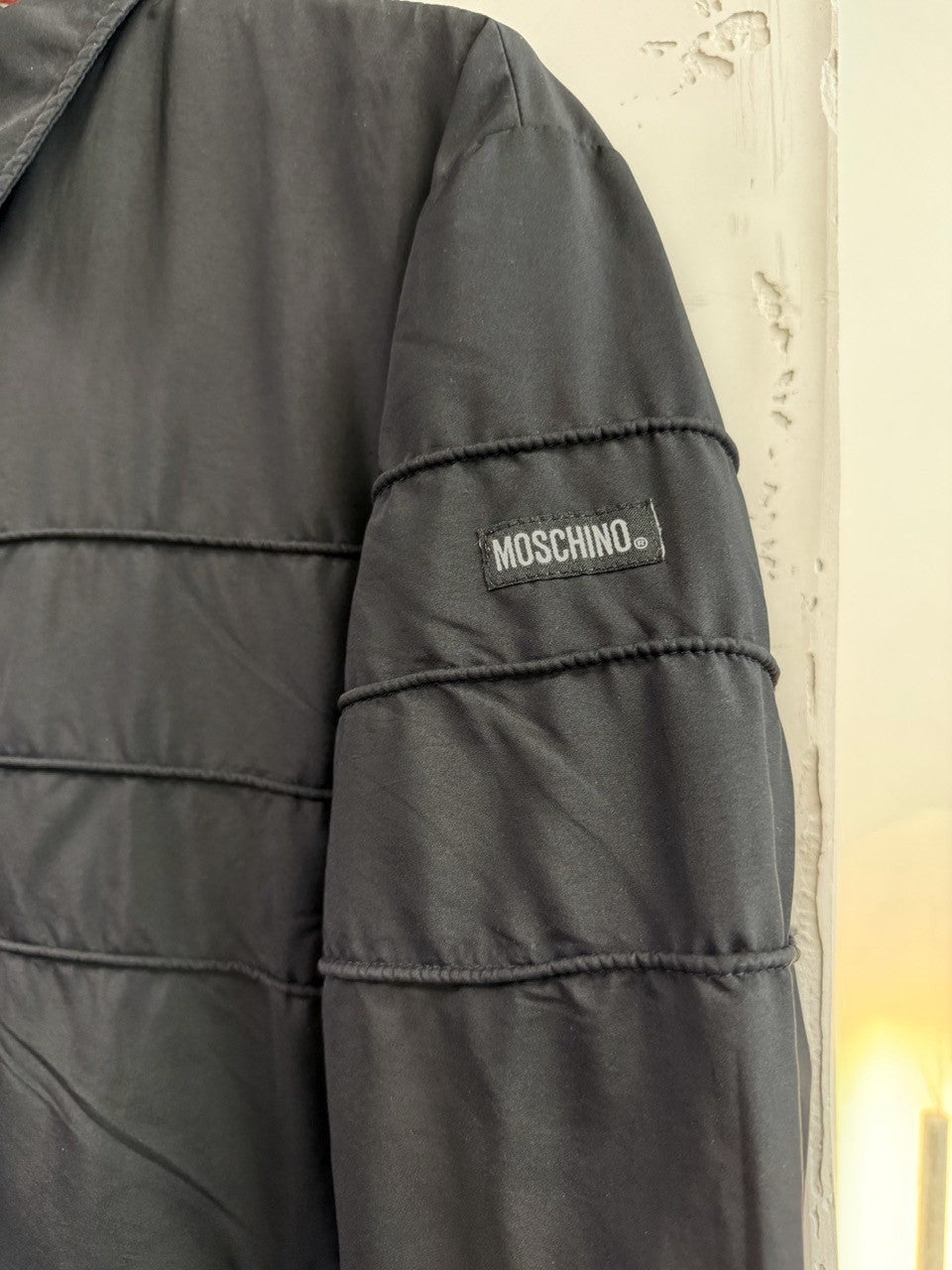 BERLIN VINTAGE CORNER black Moschino zip-up jacket with horizontal seam detailing and logo patch on sleeve.