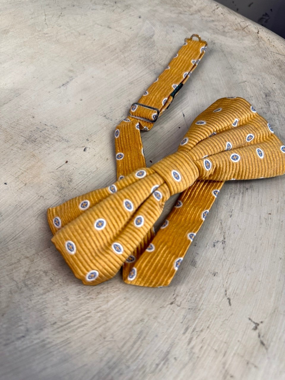 BERLIN VINTAGE CORNER mustard yellow corduroy bow tie with blue and white oval pattern. Adjustable strap.