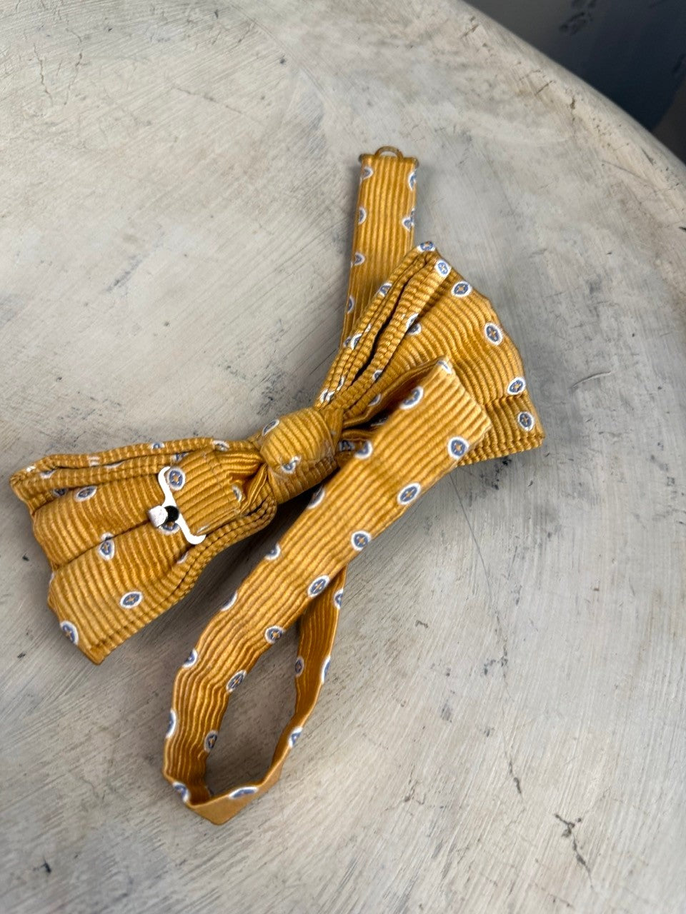 BERLIN VINTAGE CORNER mustard yellow corduroy bow tie with blue and white oval pattern. Pre-tied with adjustable strap.