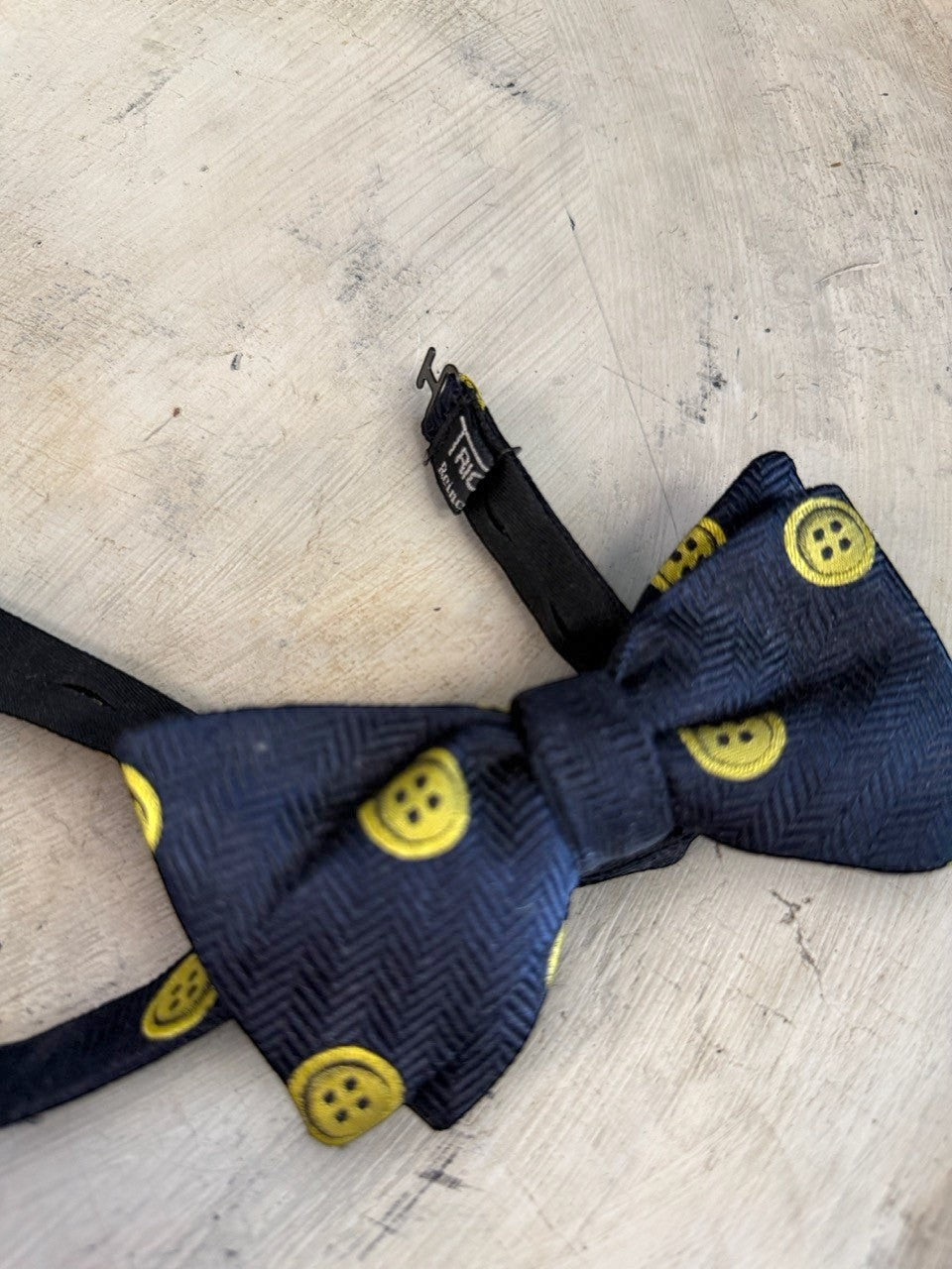 BERLIN VINTAGE CORNER navy blue bow tie with yellow button pattern and herringbone texture.