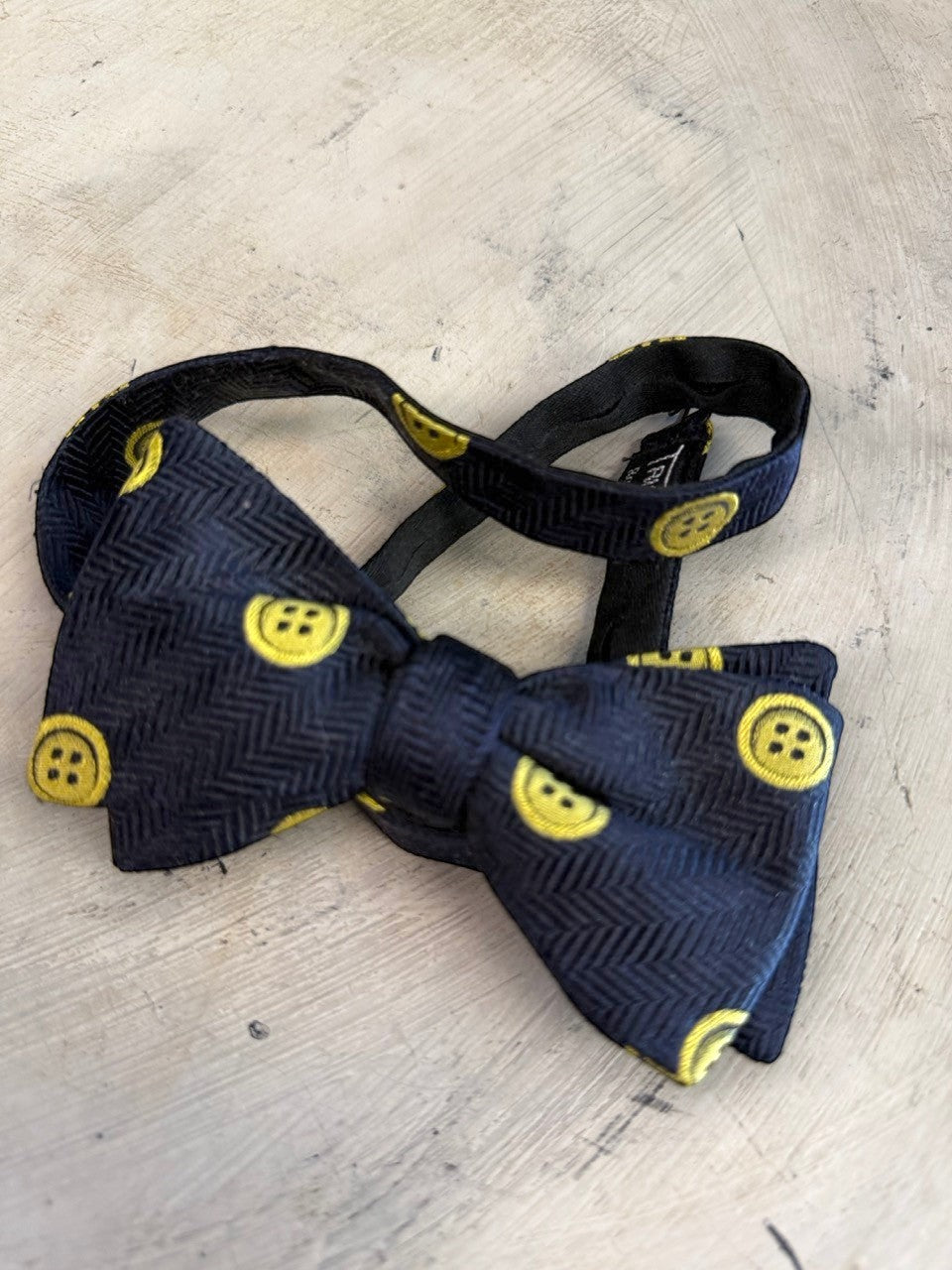 BERLIN VINTAGE CORNER navy blue bow tie with yellow button pattern and herringbone texture. Adjustable strap.