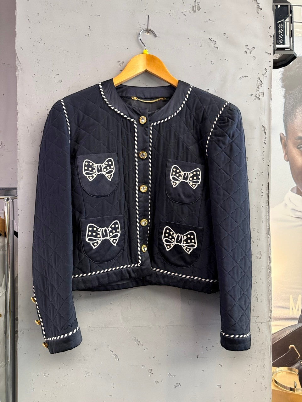 BERLIN VINTAGE CORNER navy quilted jacket with white piping, jeweled buttons, and embroidered bow appliques on pockets.