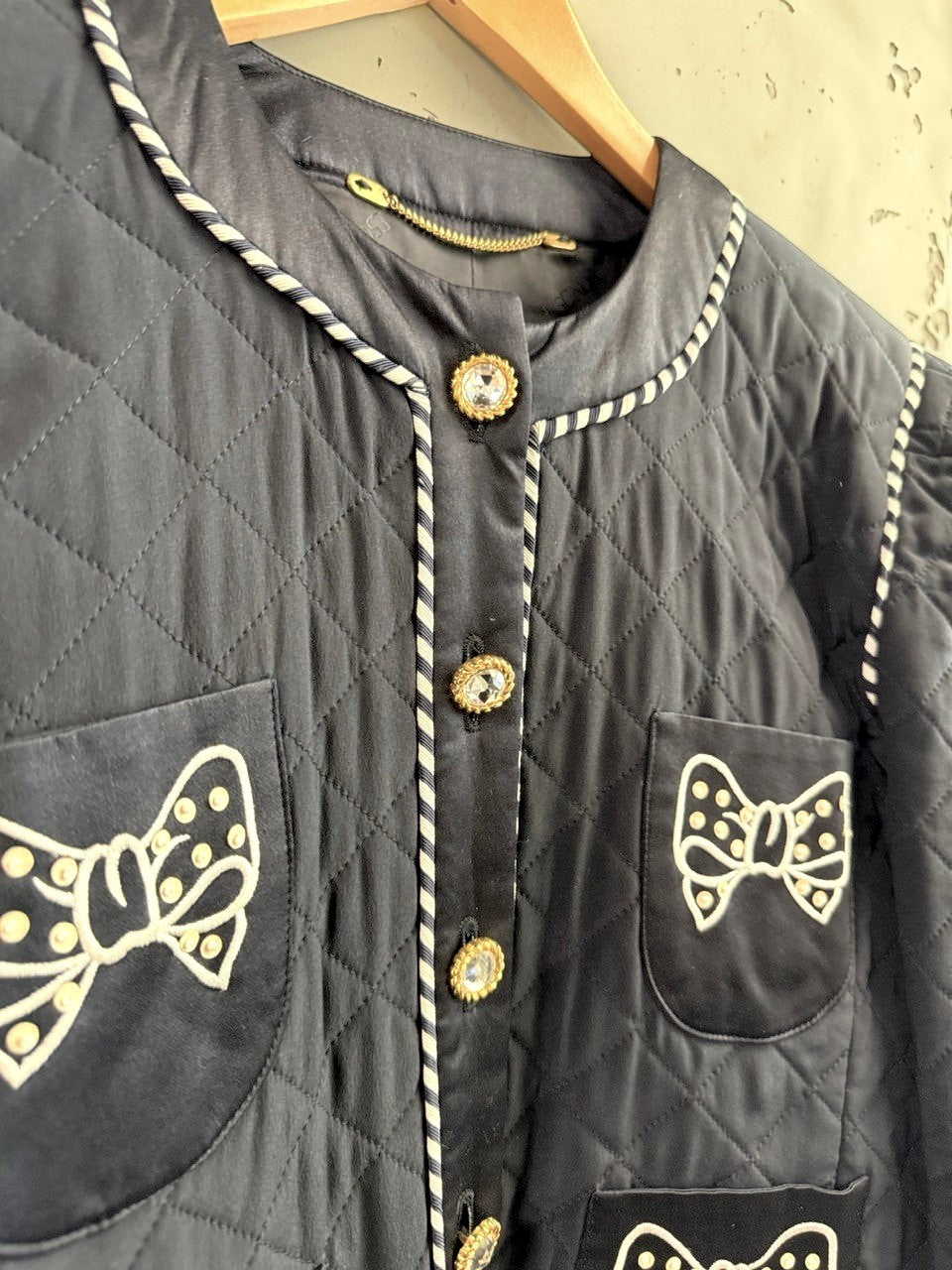 BERLIN VINTAGE CORNER navy quilted jacket with jeweled buttons and embroidered bow appliques on pockets.