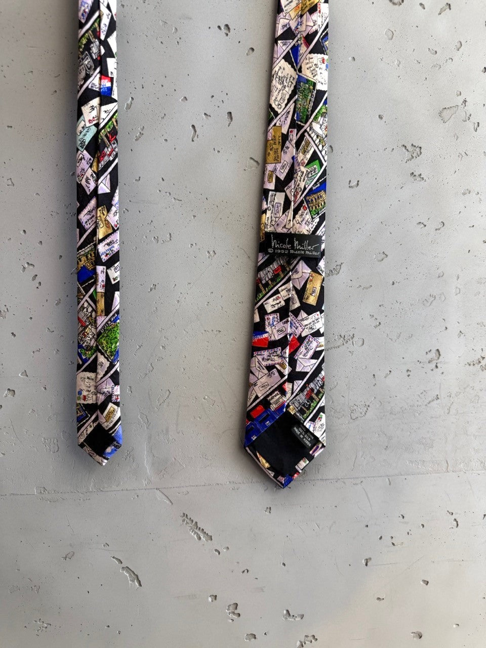 BERLIN VINTAGE CORNER Nicole Miller 1992 black silk necktie with a collage of envelopes, stamps, and landmarks.