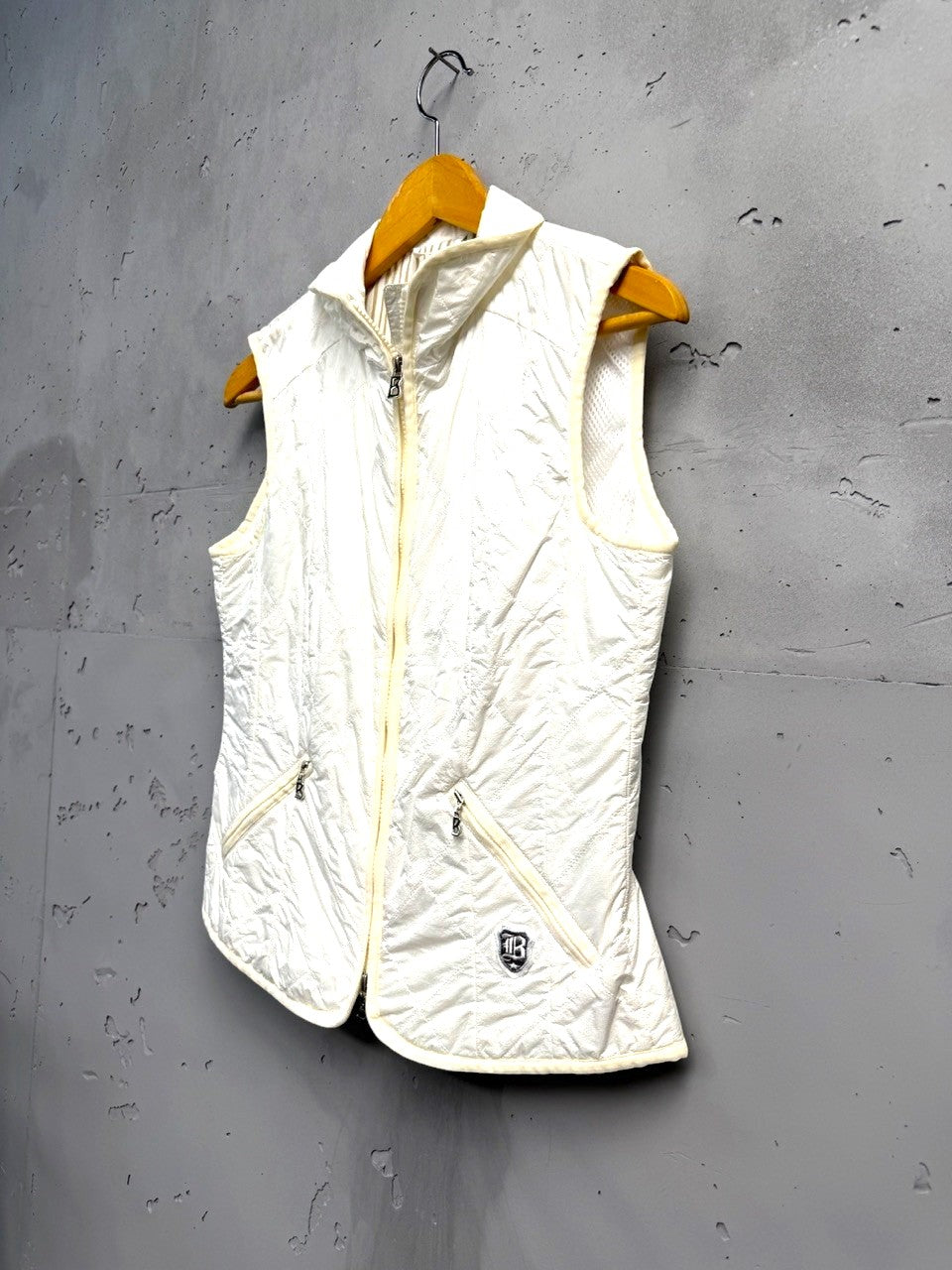 BERLIN VINTAGE CORNER off-white quilted padded vest with zip front, stand-up collar, and zippered pockets.