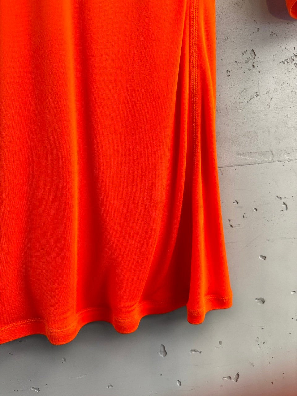 BERLIN VINTAGE CORNER vibrant orange long sleeve top made of stretchy fabric with side seam detail.