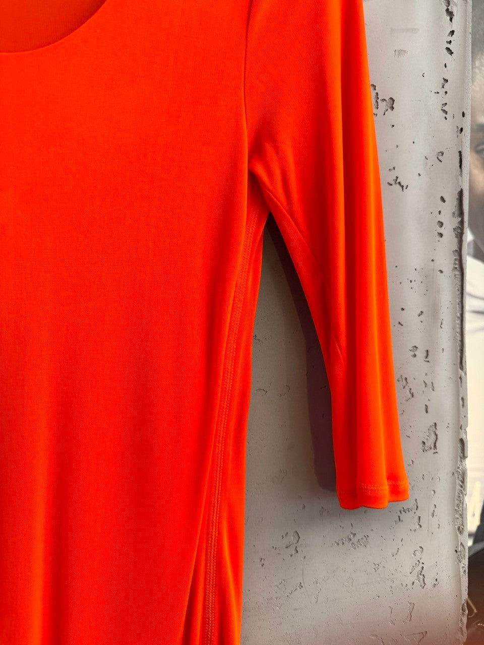 BERLIN VINTAGE CORNER vibrant orange stretchy long sleeve top with subtle side seam detail.