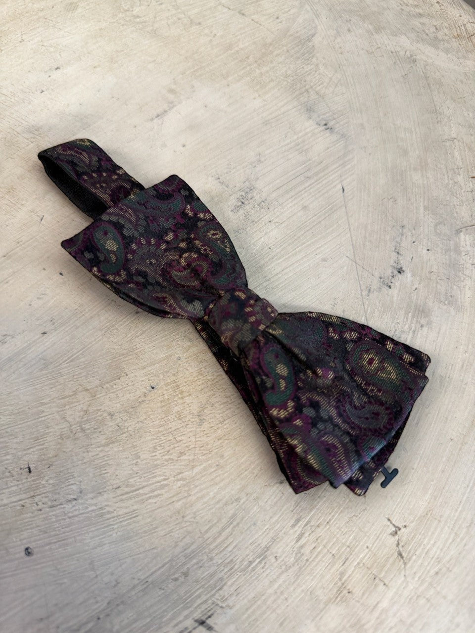 BERLIN VINTAGE CORNER paisley patterned silk bow tie in burgundy, green, and gold on a dark background. Adjustable strap.