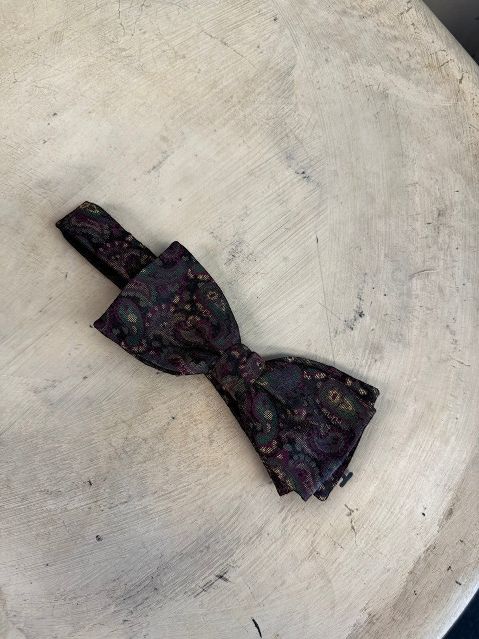 BERLIN VINTAGE CORNER paisley patterned silk bow tie in burgundy, green, and gold on a dark background. Adjustable strap.