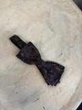 BERLIN VINTAGE CORNER paisley patterned silk bow tie in burgundy, green, and gold on a dark background. Adjustable strap.