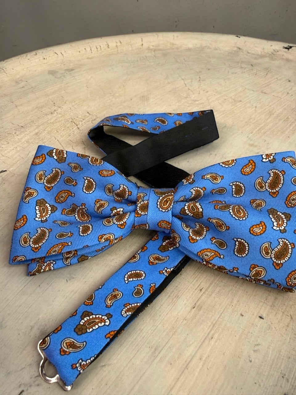 BERLIN VINTAGE CORNER sky blue bow tie with brown and orange paisley pattern. Adjustable strap.