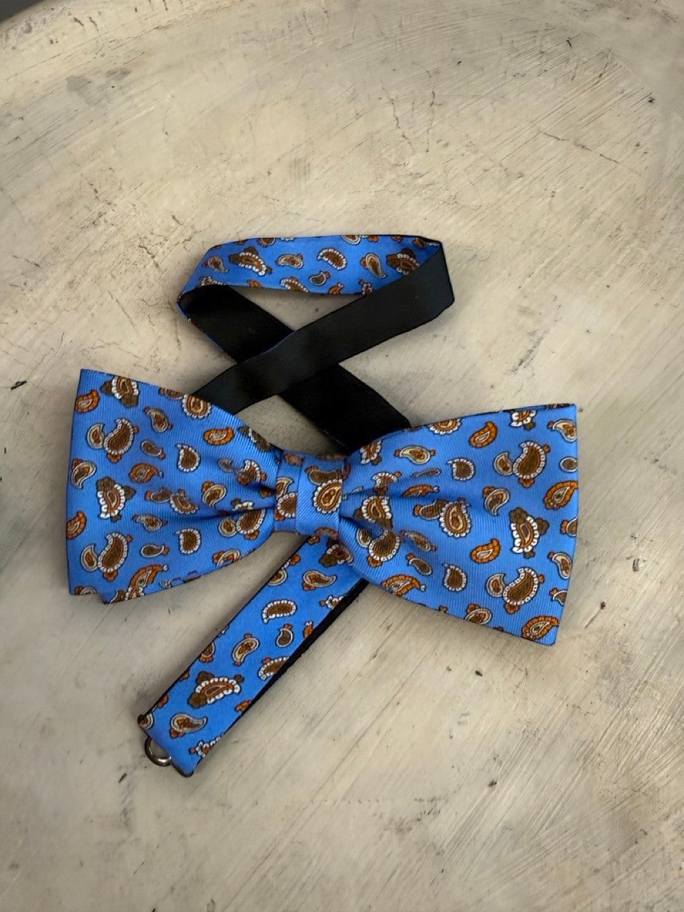 BERLIN VINTAGE CORNER sky blue bow tie with brown and burnt orange paisley pattern. Adjustable strap.