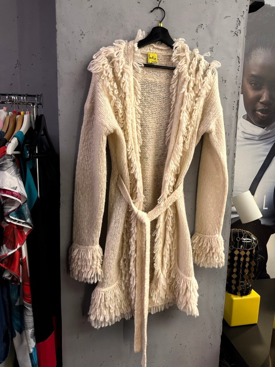 BERLIN VINTAGE CORNER Paul Smith cream chunky knit cardigan with fringe trim and tie-waist belt on a hanger.