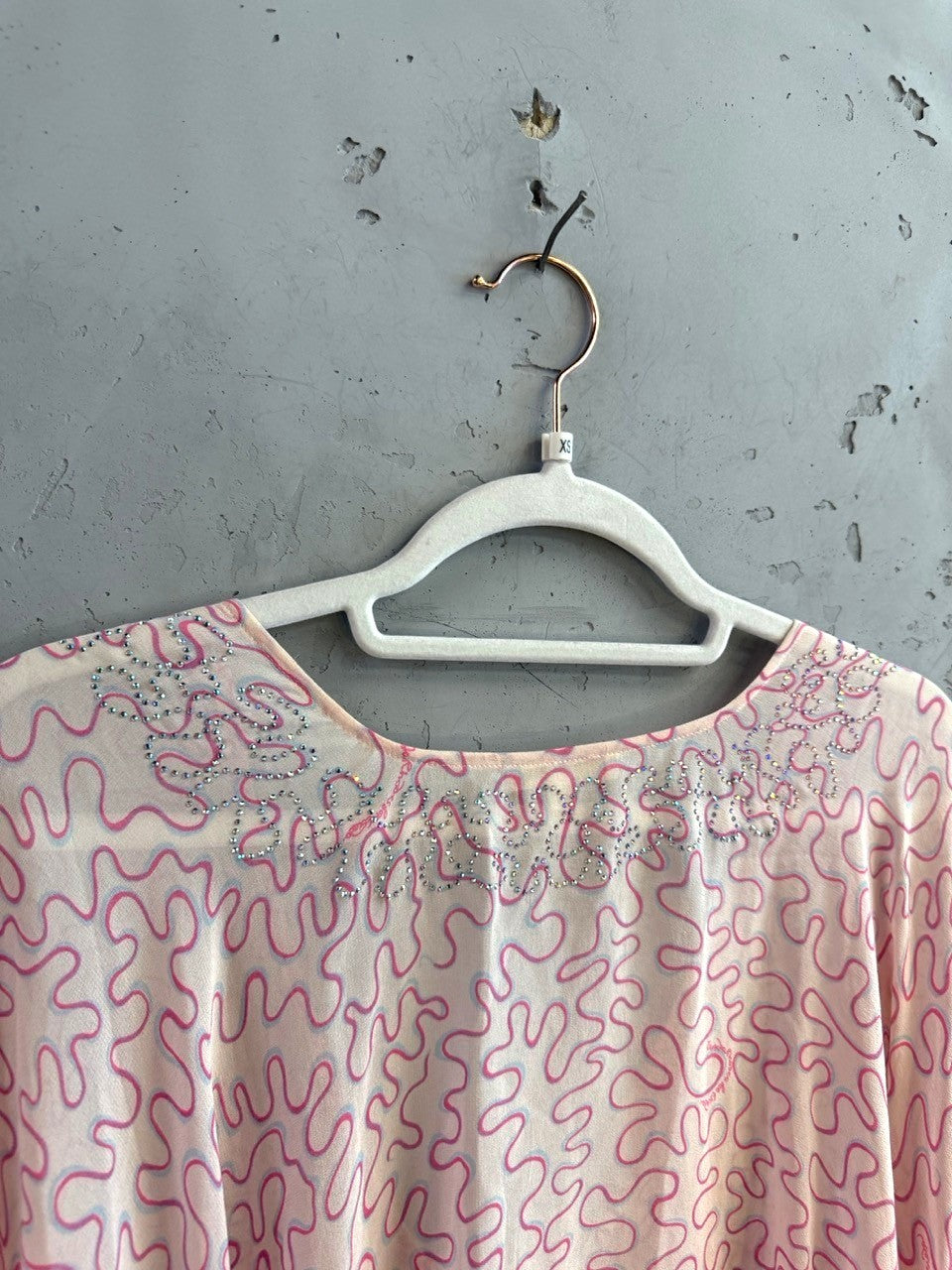 BERLIN VINTAGE CORNER kaftan top with pink squiggle pattern and crystal-embellished neckline on a white hanger