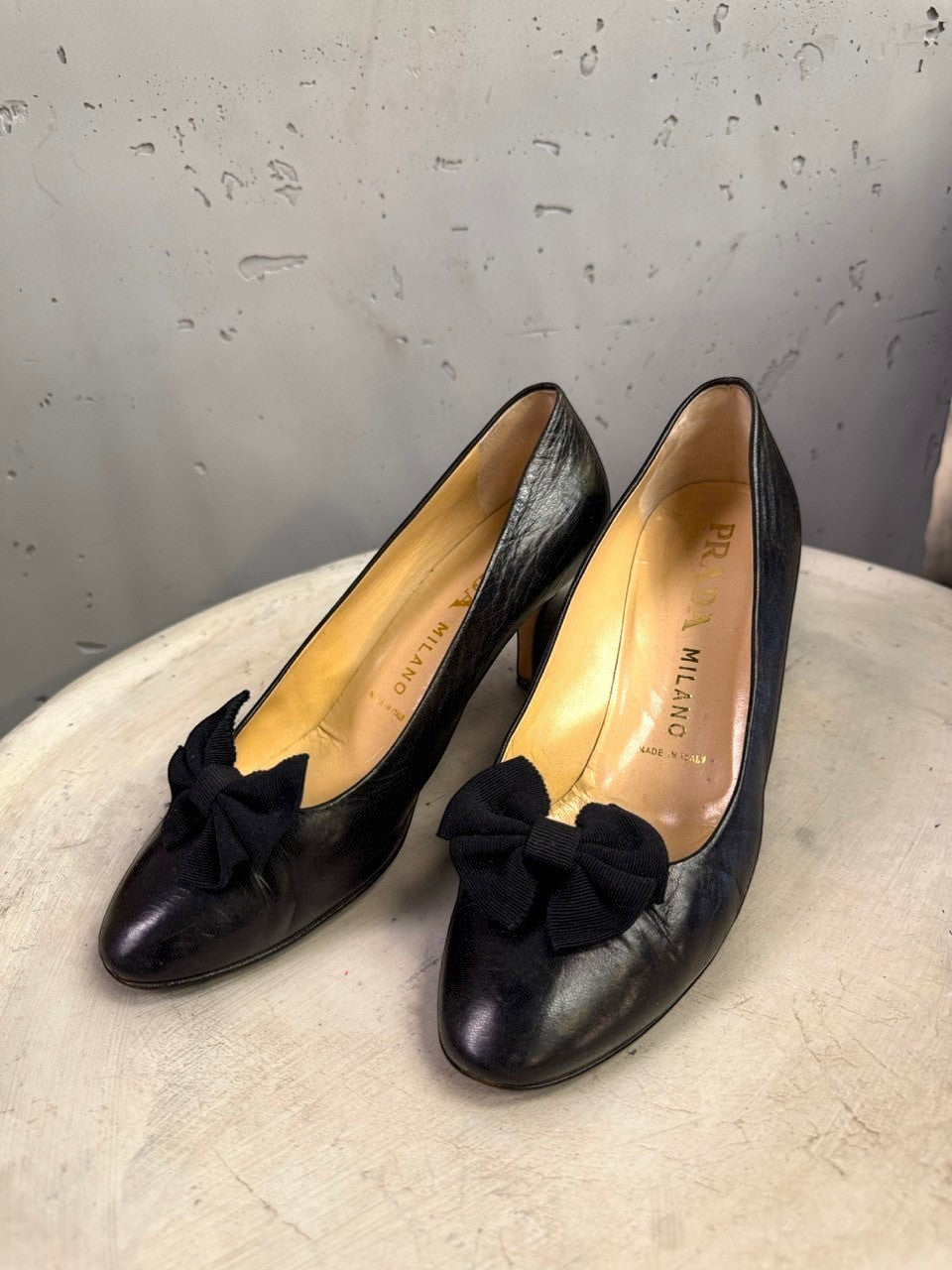 BERLIN VINTAGE CORNER black leather Prada pumps with bow detail and almond toe on a white pedestal