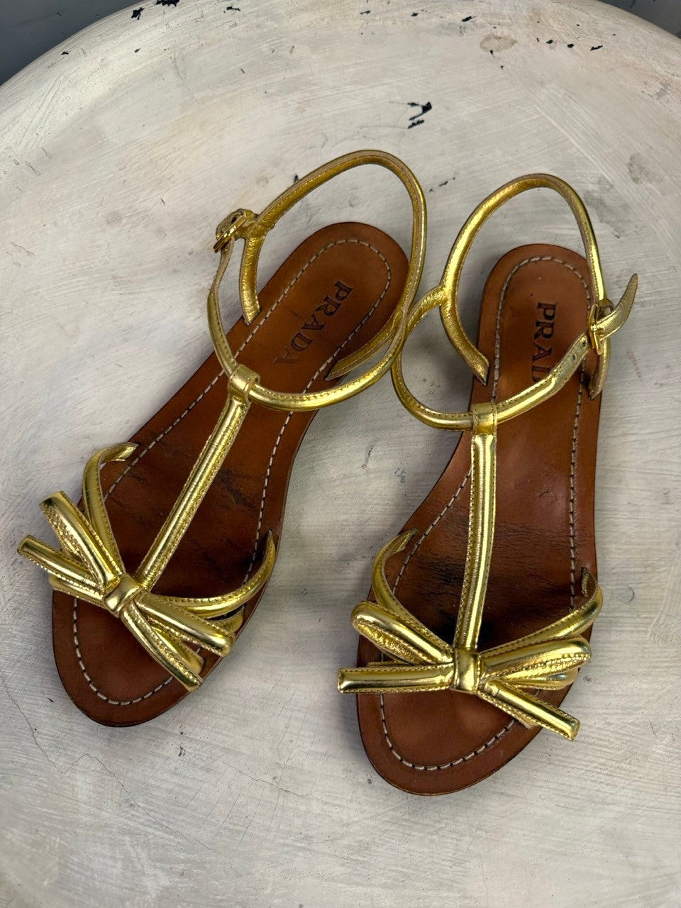 BERLIN VINTAGE CORNER Prada metallic gold leather flat sandals with bow detail and adjustable ankle strap.