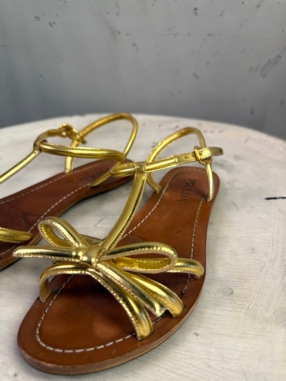 BERLIN VINTAGE CORNER Prada metallic gold leather flat sandals with a delicate bow detail and adjustable ankle strap.