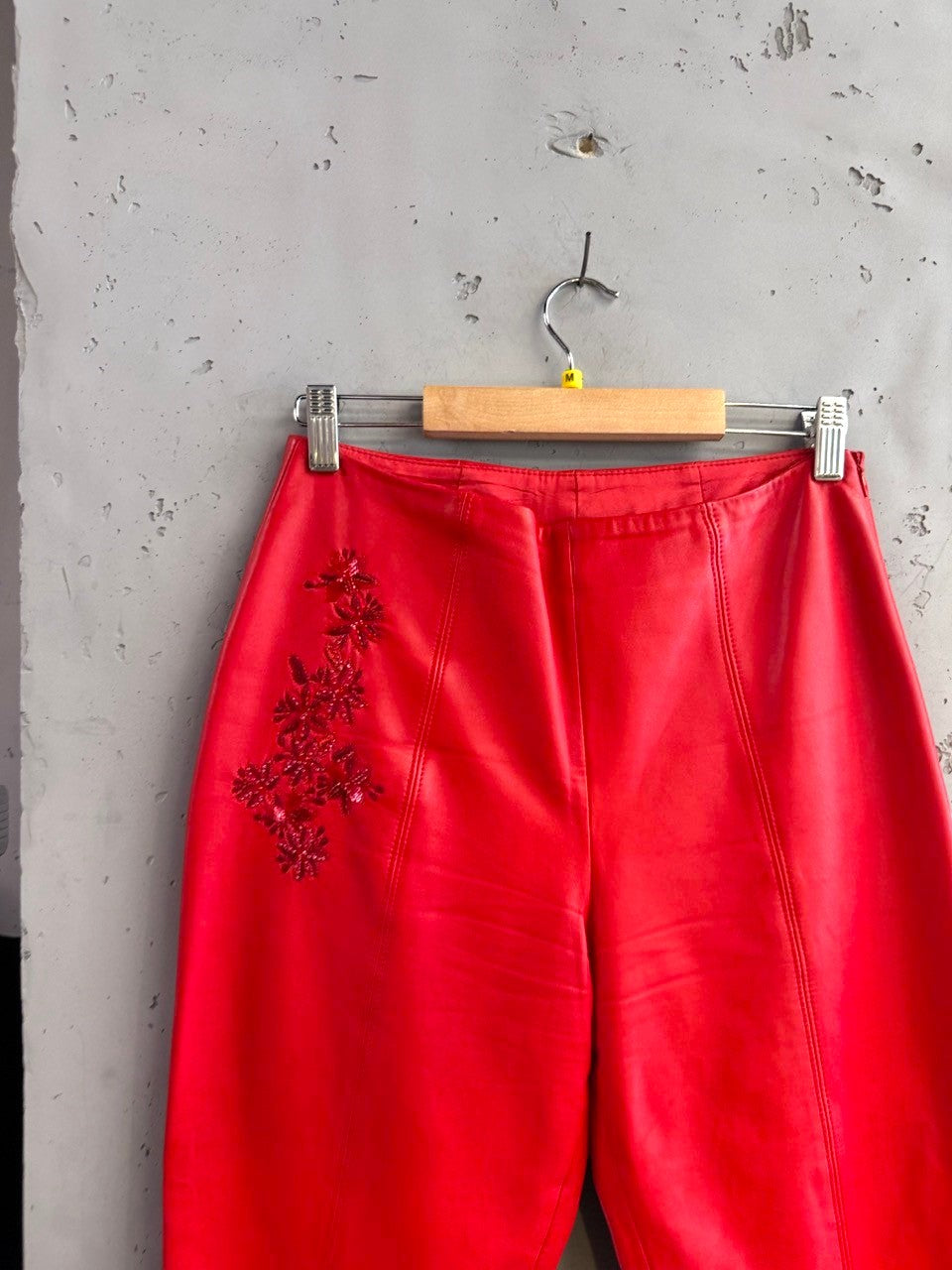 BERLIN VINTAGE CORNER red leather cropped pants with intricate floral beadwork on the left hip.