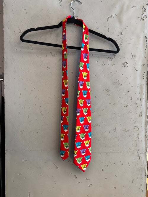 BERLIN VINTAGE CORNER red silk necktie with all-over print of colorful jaguar heads. Features purple, yellow, green, and blue jaguar faces.