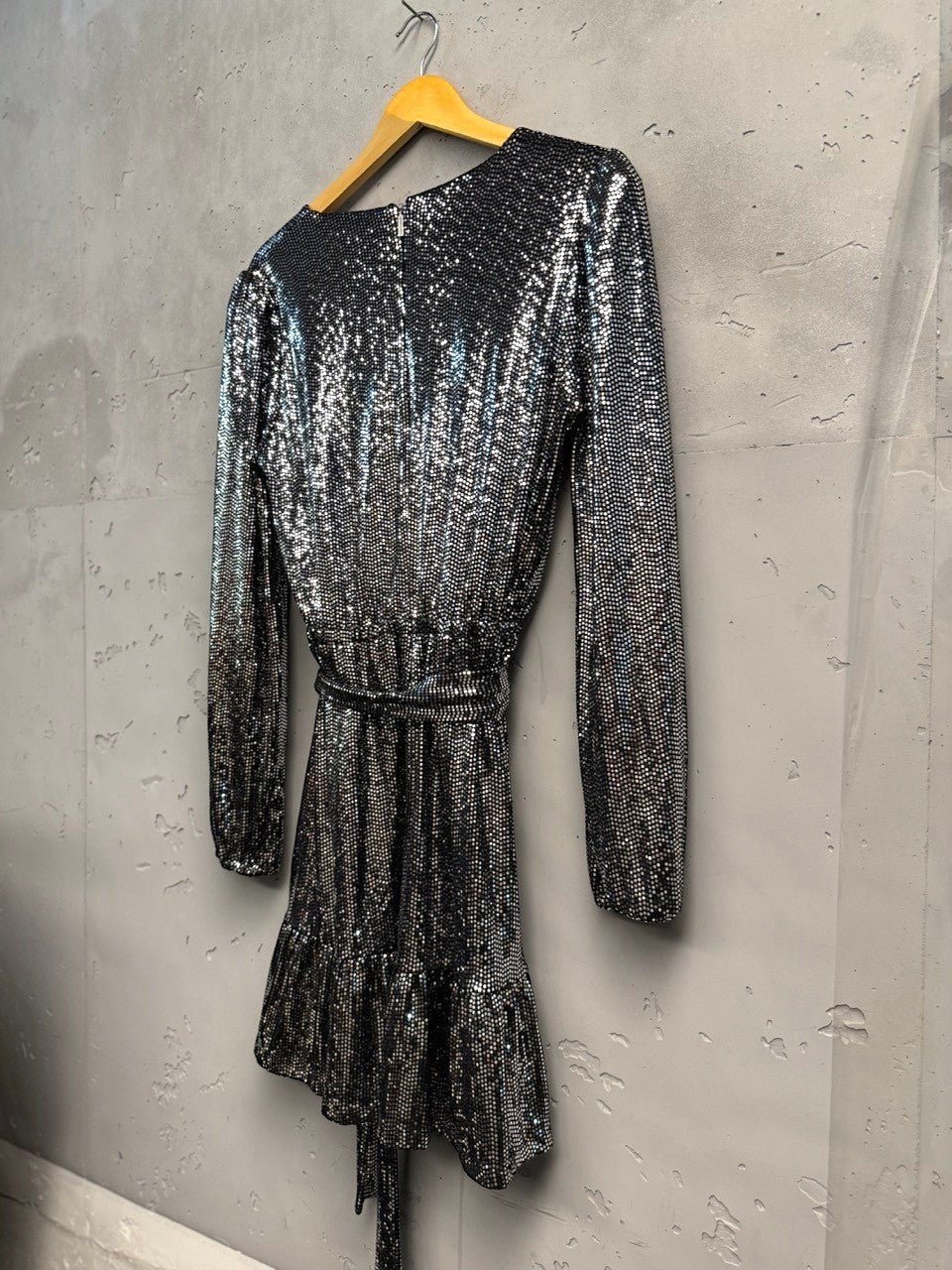 BERLIN VINTAGE CORNER silver sequin wrap dress with V-neck, long sleeves, tie waist, and ruffled hem.