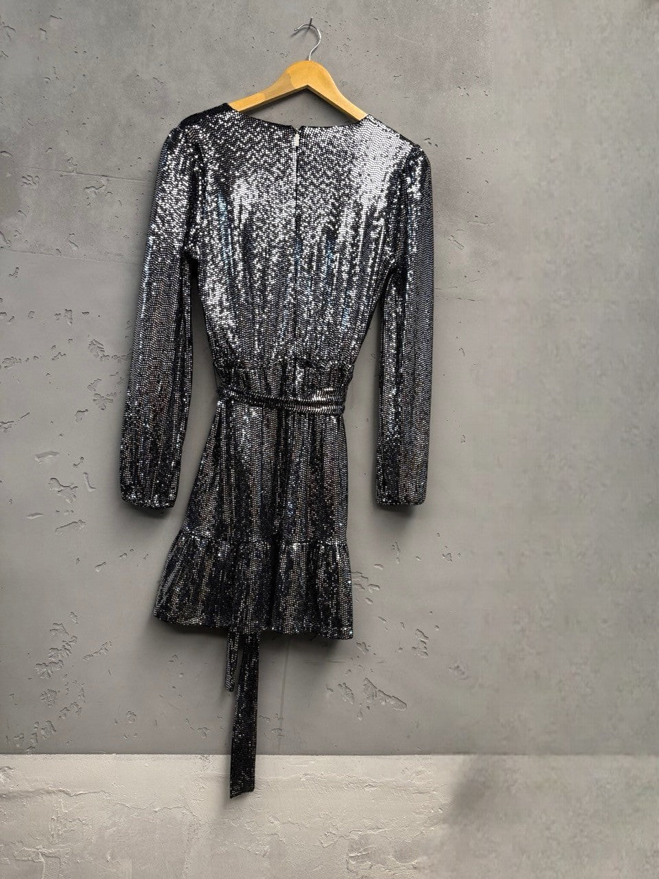 BERLIN VINTAGE CORNER silver sequin wrap dress with long sleeves, V-neckline, tie waist, and ruffled hem.