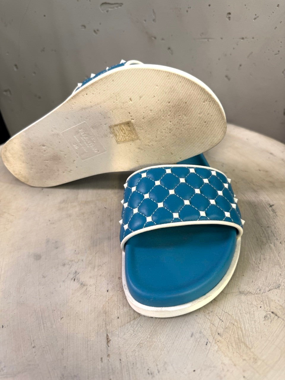 BERLIN VINTAGE CORNER teal slide sandals with white trim and quilted strap adorned with studs.
