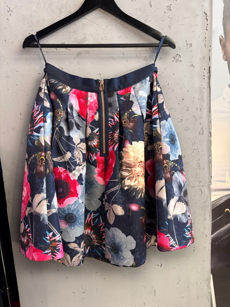 BERLIN VINTAGE CORNER Ted Baker navy floral A-line skirt with a prominent metallic back zipper on a hanger.