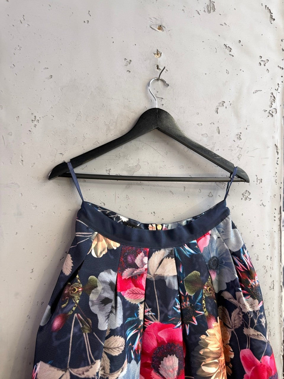 BERLIN VINTAGE CORNER Ted Baker navy floral print A-line skirt with a back zipper hanging on a black hanger.