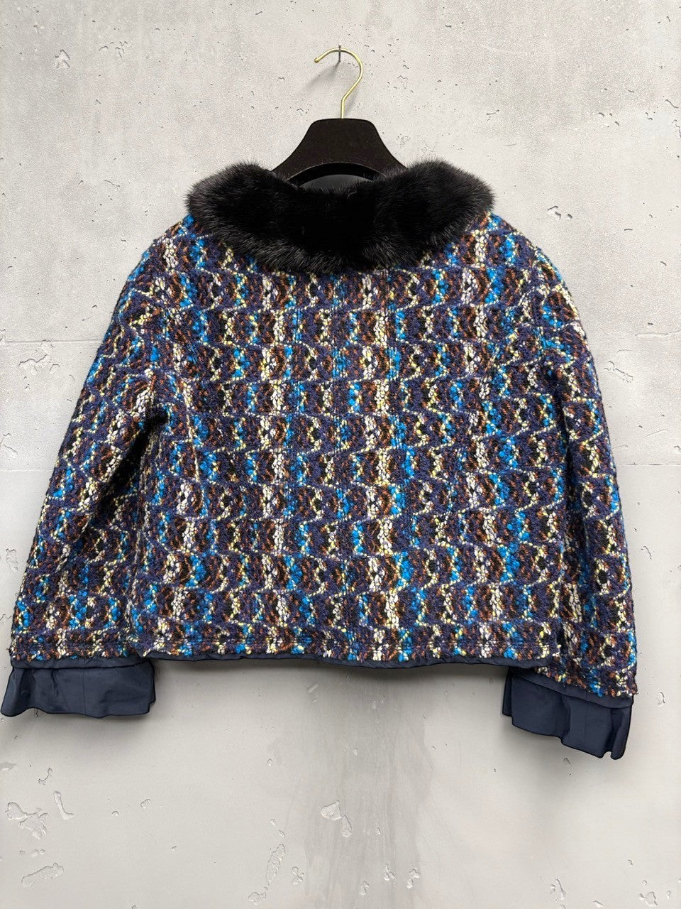 BERLIN VINTAGE CORNER textured cropped jacket with blue, brown, and yellow tweed, black fur collar, and ruffled cuffs.