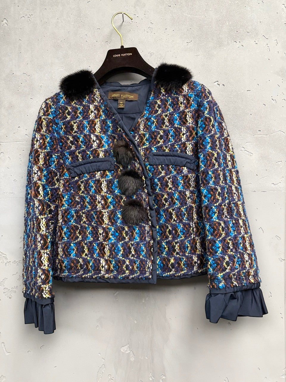 BERLIN VINTAGE CORNER textured cropped jacket in blue, brown, and yellow tweed with black fur collar and pom-poms, ruffled cuffs.