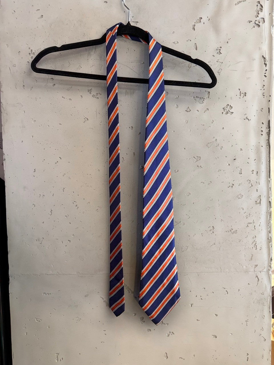 BERLIN VINTAGE CORNER Tino Cosma silk necktie featuring diagonal navy blue, orange, and white stripes on a hanger.
