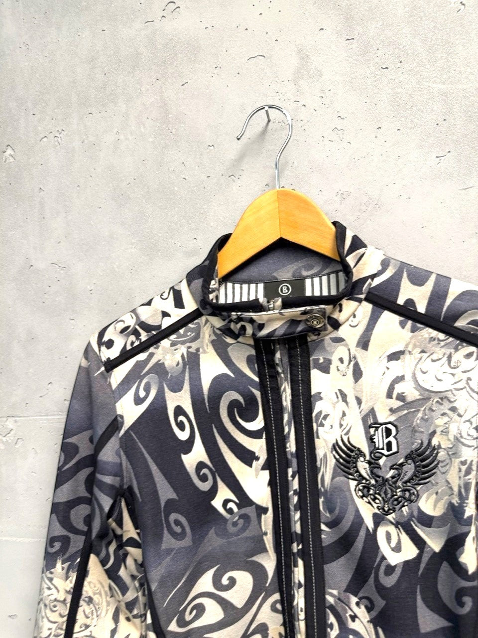 BERLIN VINTAGE CORNER grey, black, and cream tribal print zip-up jacket with stand-up collar and embroidered chest detail.