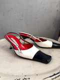 BERLIN VINTAGE CORNER two-tone leather slingback heels with black toe, white body, red lining, and buckle detail.