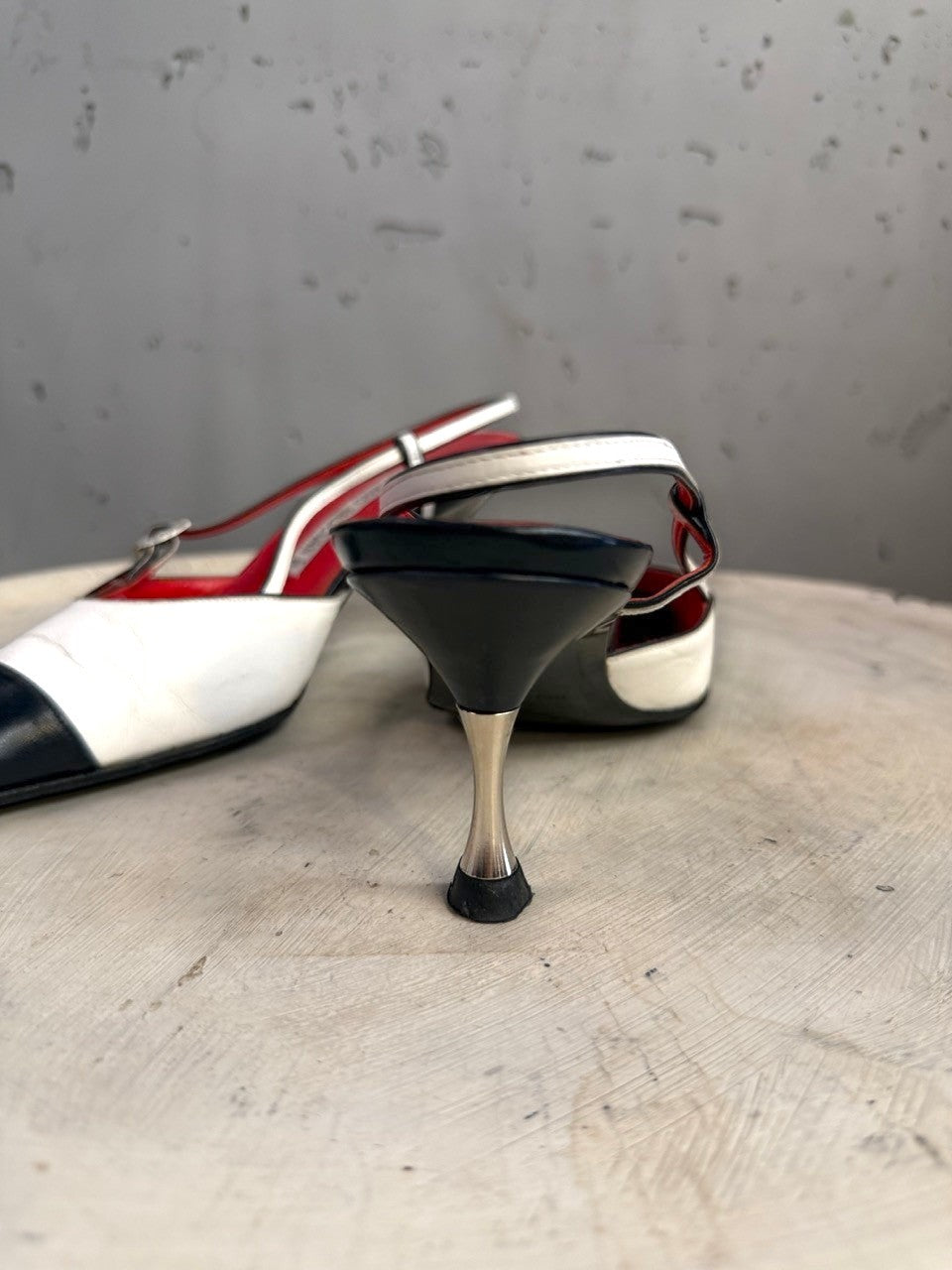 BERLIN VINTAGE CORNER two-tone leather slingback heels with black toe, white upper, red lining, and metallic heel.