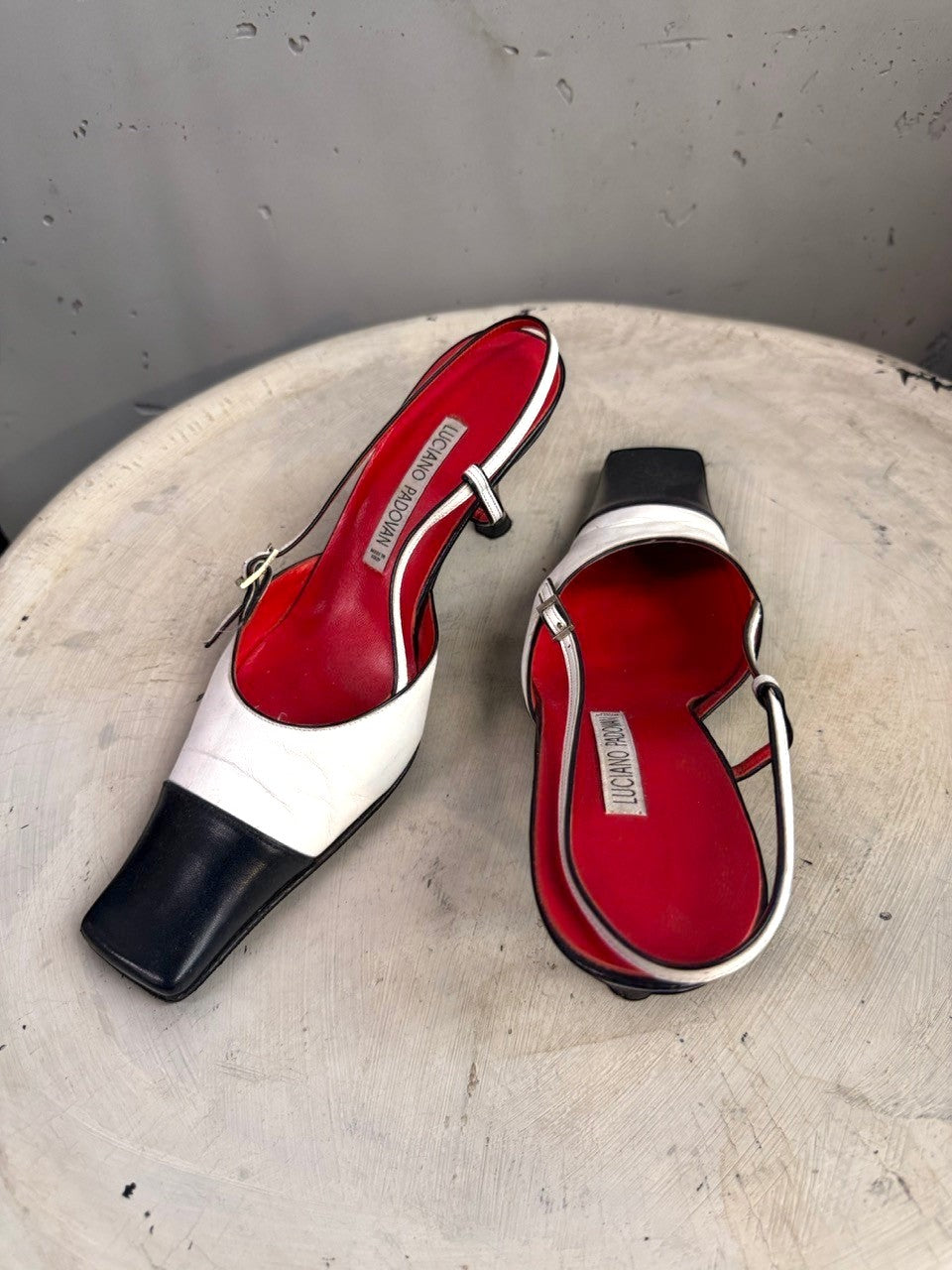 BERLIN VINTAGE CORNER two-tone leather slingback heels with black toe cap, white upper, red lining, and buckle detail.