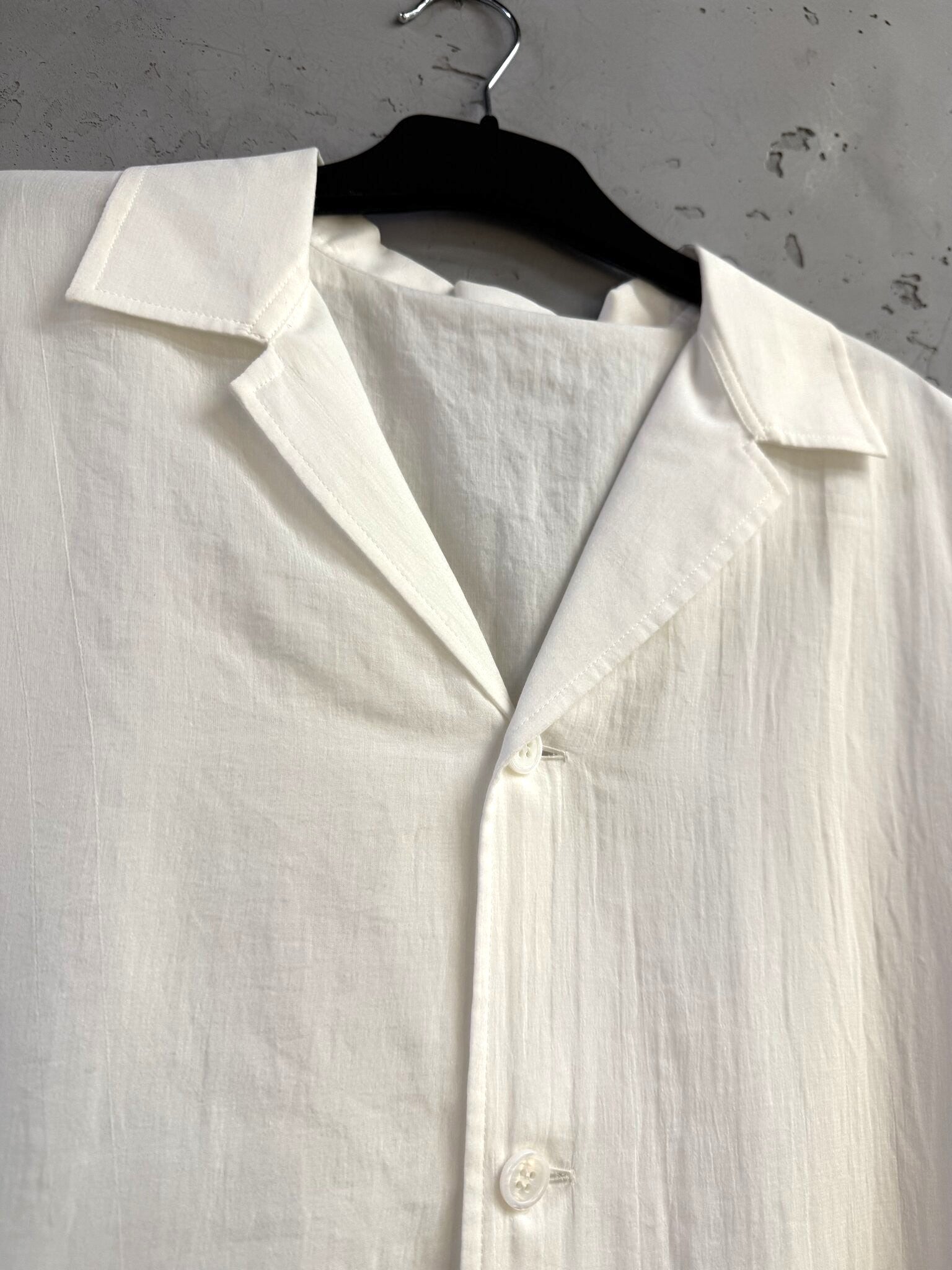 BERLIN VINTAGE CORNER white oversized cotton button-down shirt with a notched collar hanging on a black hanger.