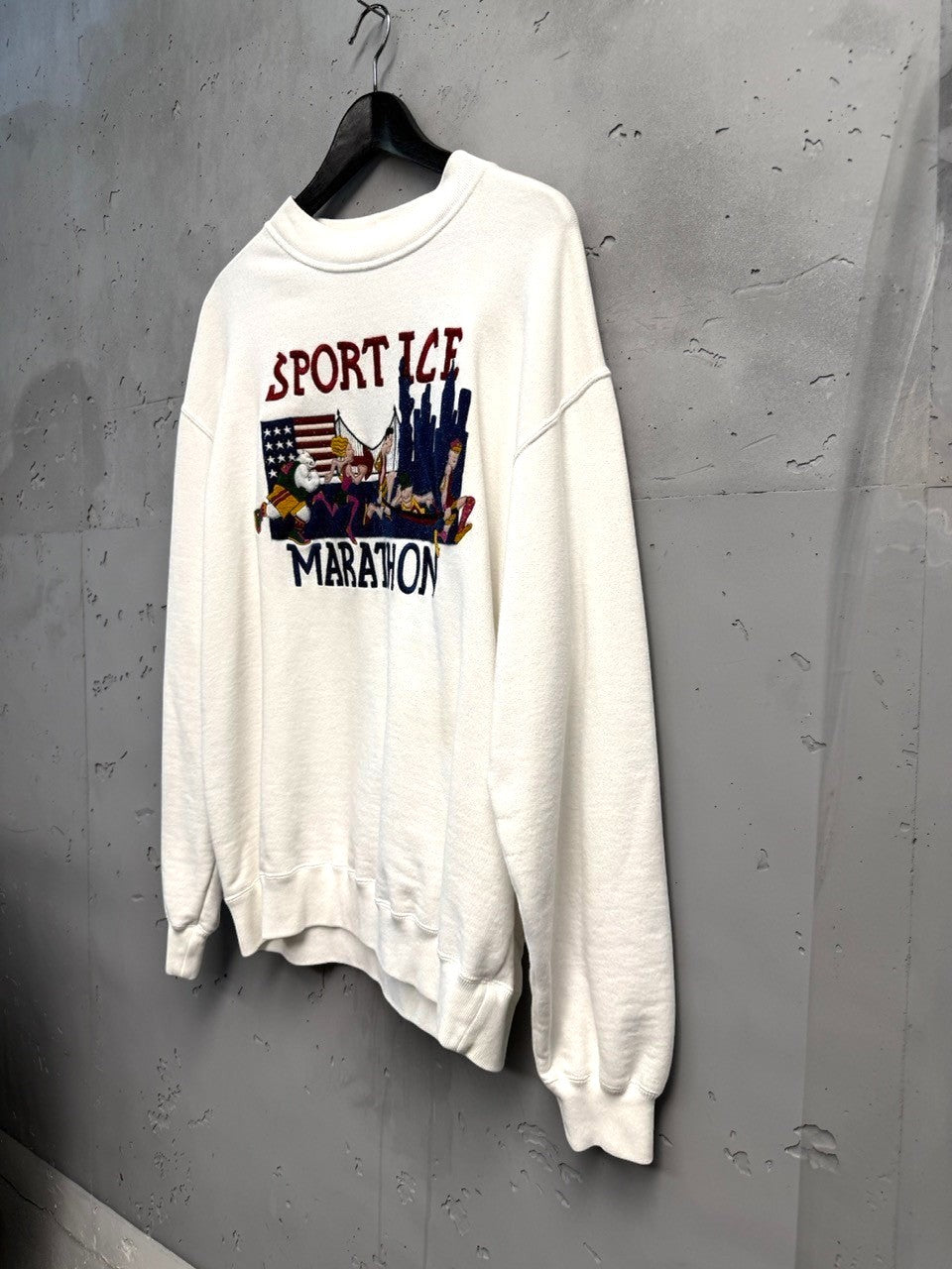 BERLIN VINTAGE CORNER white crewneck sweatshirt with Sport Ice Marathon graphic, American flag, and cityscape. Vintage athletic style.