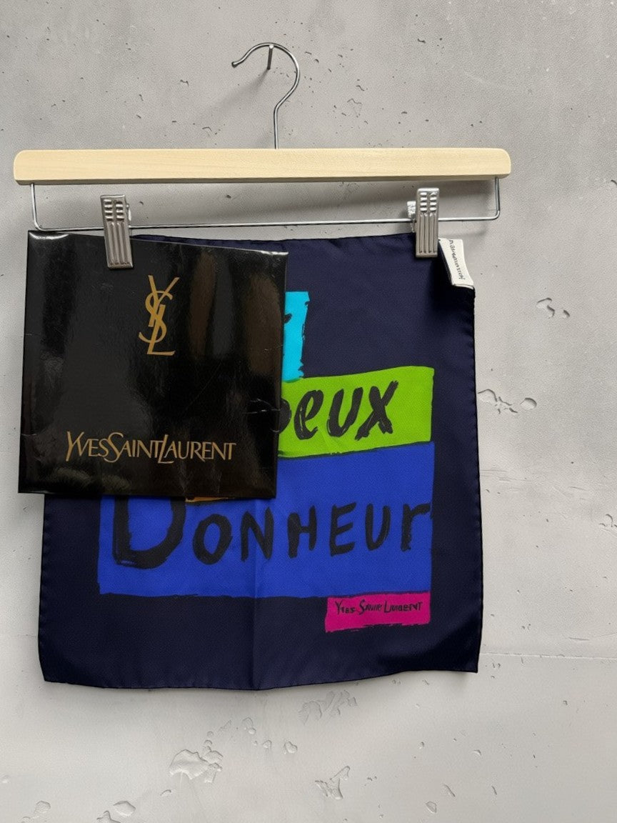 BERLIN VINTAGE CORNER Yves Saint Laurent navy silk scarf with graphic print of colorful text blocks.
