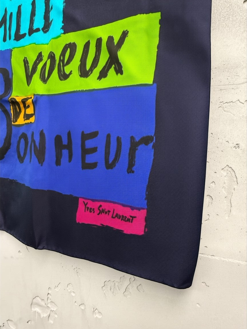 BERLIN VINTAGE CORNER Yves Saint Laurent navy silk scarf with bold graphic print in cyan, lime green, blue, and pink. Features text and logo.
